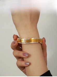 Detailed view of hollow gold-plated wave bangle with sparkling white cubic zirconia