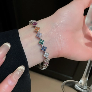 Macro shot of a silver clover bracelet with colorful zircons worn on a female wrist
