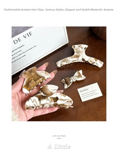 Detail of vintage cream acetate hair claws with marble texture and gold branding