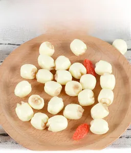 Detailed top view of realistic white PVC lotus seeds with red wolfberry in a wooden tray