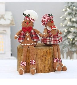 Close-up of plush gingerbread couple in festive red checkered outfits on rustic wood