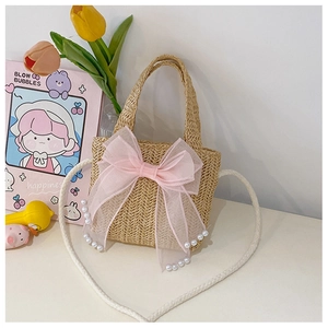 Detail of handmade straw bag with pink gauze bow, white pearls and braided strap