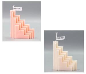 Macro detail of geometric S-shaped scented candles in pastel pink and cream white
