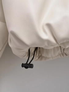 Detailed close-up of cream leather jacket hem with adjustable black drawstring toggles