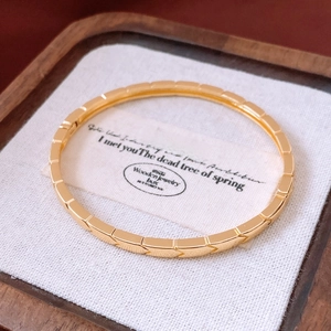 Gros plan détaillé d'un bracelet doré à motifs géométriques sur un coussin blanc