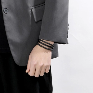 Close-up of men's multi-layer black lava stone beads and woven leather bracelet set