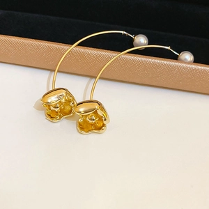 Macro shot of elegant golden flower earrings featuring a curved bar and a lustrous pearl