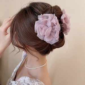 Detail einer fliederfarbenen Stoffblume-Haarklammer in einer eleganten Hochsteckfrisur