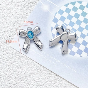 Macro shot of silver bow pendants with blue gemstone and 18mm by 19.5mm size marking