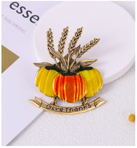 Detail of pumpkin brooch with wheat and Give thanks banner on white pedestal