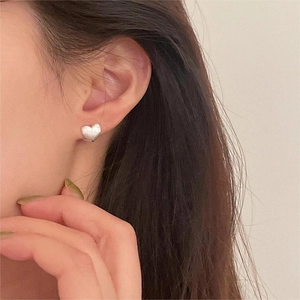Close-up of matte brushed silver heart earring worn to show refined metal texture and style
