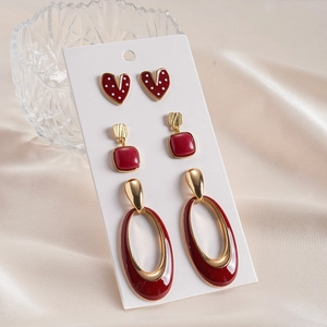 6-piece set of red enamel heart and geometric earrings on a display card with silk background