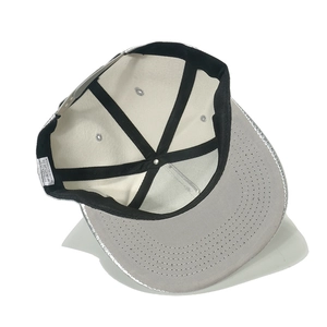 Internal detail of a baseball cap showing white six-panel structure and 100% acrylic label