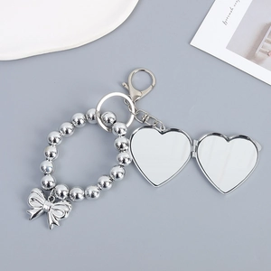 Silver beaded keychain with bow pendant and heart-shaped folding mirror charm accessory