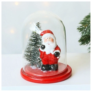 Close-up of a lit Christmas glass dome with Santa Claus figurine and a red base