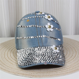 Detailed close-up of light blue denim baseball cap with sparkling rhinestones and white floral 3D decor