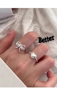 Close-up of S925 silver bow and heart-shaped beaded rings with a polished metal finish
