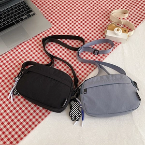 Detail of nylon crossbody bags in black and blue with adjustable straps and bear charm