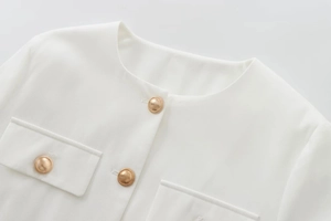 Close-up of white tweed jacket featuring decorative golden dome metal buttons and texture