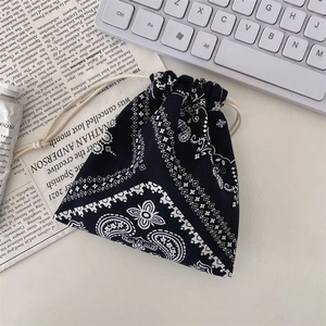 Detail of a black paisley drawstring bag on a newspaper background with a white keyboard