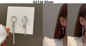Macro detail of asymmetric silver tassel earrings with zircon studs on model