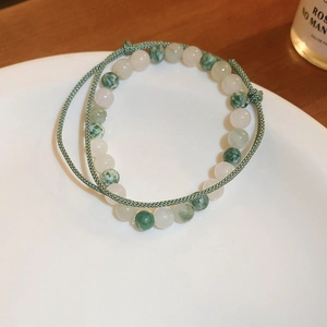 Détail d'un bracelet en perles vertes avec cordon tressé réglable sur plat blanc