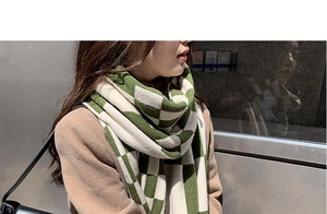 Detail of green and white checkerboard knit scarf on model for warm winter style