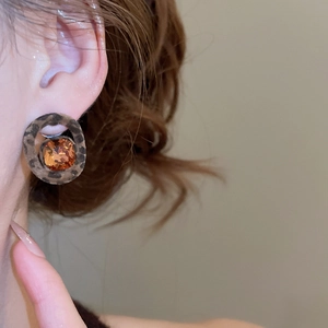 Detail of leopard print ring earring with amber faceted gemstone on model's ear