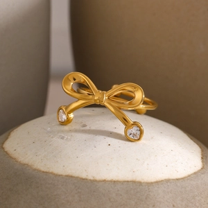 Detail of 18k gold plated bow ring featuring heart-shaped zircon stones on ribbon ends