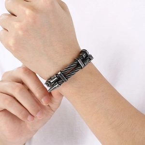 Detail of punk style black steel cable bracelet with silver spike and cylinder accents