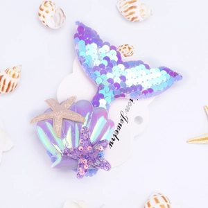 Close-up of sequined mermaid tail hair clip with seashells and starfish on card