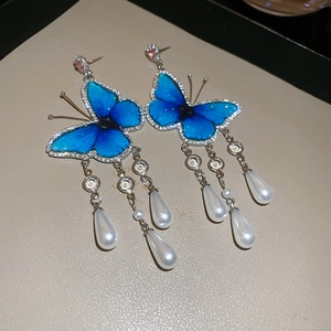 Vintage blue butterfly earrings with pearl tassels on a minimalist jewelry tray