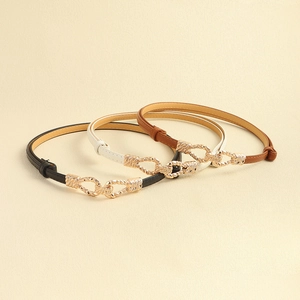 Three skinny leather belts in black, white, and brown with decorative gold metal buckles