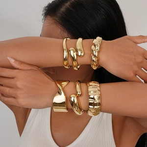 Stack of chunky gold irregular open bracelets and twisted metallic bangles for women