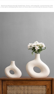Detail of minimalist white ceramic vases with hollow design and matte finish