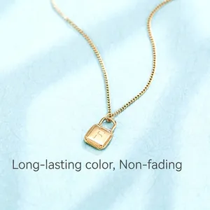 Gold padlock pendant necklace with letter F engraving on blue textured background