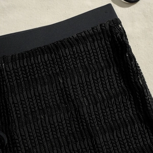 Detail of black crochet bikini cover-up with textured knit pattern and elastic waistband