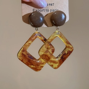 Detail of vintage resin hoop earrings featuring amber tortoiseshell texture and geometric shapes