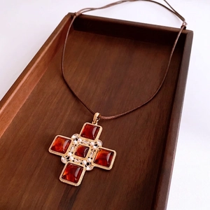 Vintage leather cord necklace with a golden cross pendant featuring amber stones and pearls