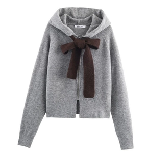 Detail of grey hooded knit cardigan featuring a large dark brown bow and zip front