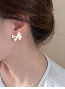 Close-up of elegant silver bow earrings with sparkling diamonds on a model's ear