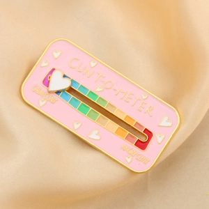 Pink enamel badge pin with rainbow slider and gold metal edges on silk fabric