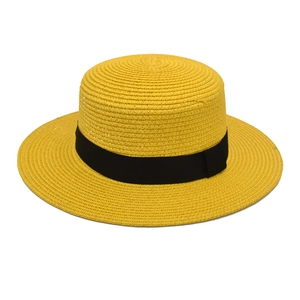 Close-up of bright yellow boater straw hat with black ribbon band and fine texture