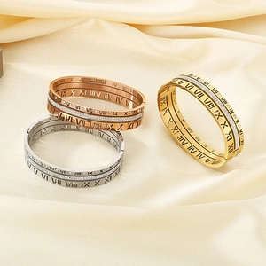 Detail of Roman numeral bangles in gold, rose gold and silver on silk background