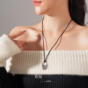 Minimalist silver oval hollow pendant necklace with black cord worn on model