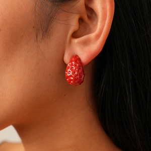 Close-up of realistic red strawberry earring with glossy finish on a female model