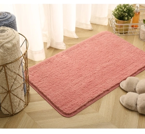 Detailed close-up of pink plush bathroom rug on wooden floor with home decor accents