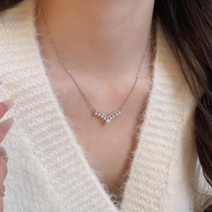 Detail of V-shaped silver necklace with gradient pearls and zircons on a model
