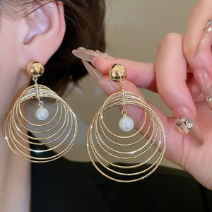 Detail of layered gold round rings earrings with a white pearl pendant for women