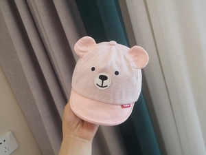 Close-up of baby sun hat featuring pink stripes and cute bear ears with facial embroidery